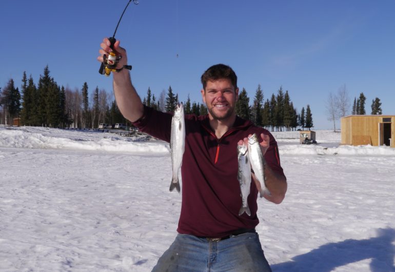 Fish On! Client with fish and ice fishing cabin in the background